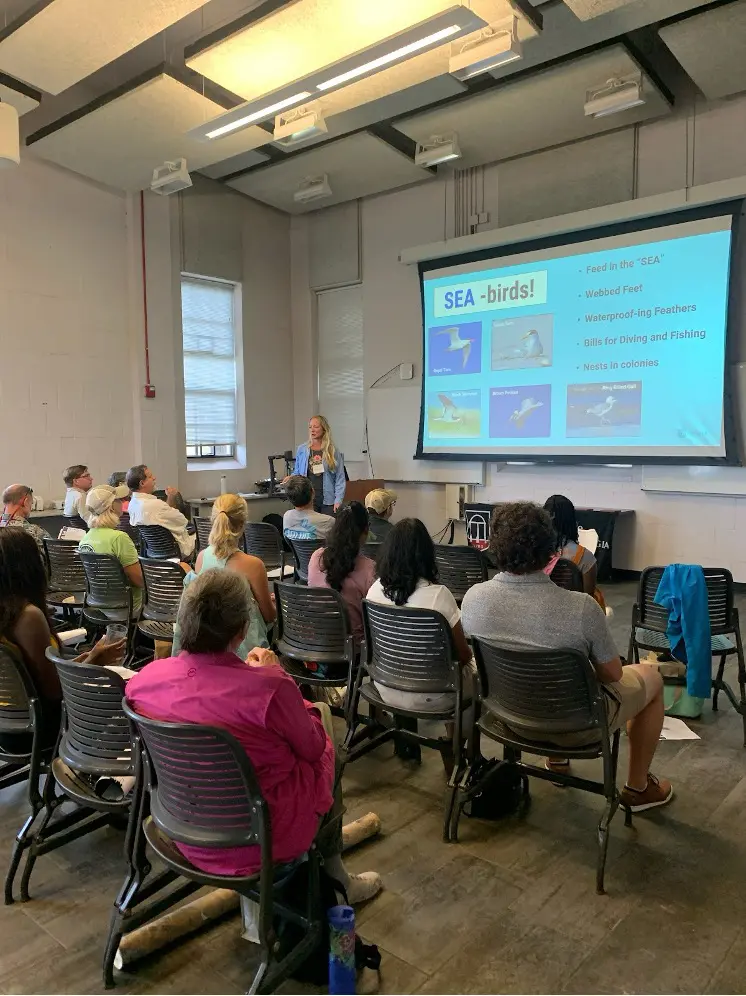 A room of people listening to a presentation